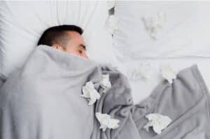 Un homme couché sous sa couette car il a un rhume