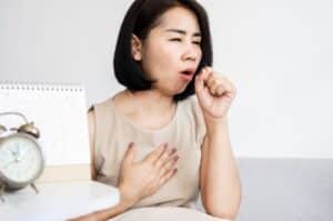 Une femme qui tousse à cause d'une bronchite chronique